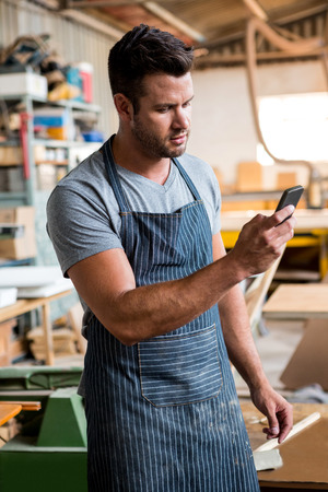 carpenter on the phone in a dusty workshopの写真素材