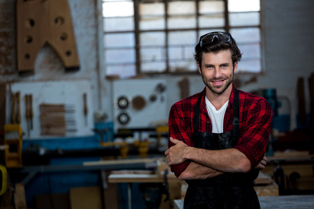 Carpenter smiling and crossing arms on his workshopの写真素材