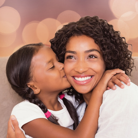 Portrait of mother and daughter holding each other on a sofaの写真素材