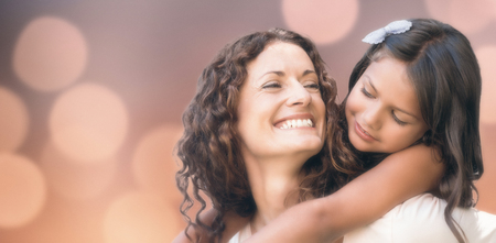 Glowing background against happy mother and daughter embracingの写真素材