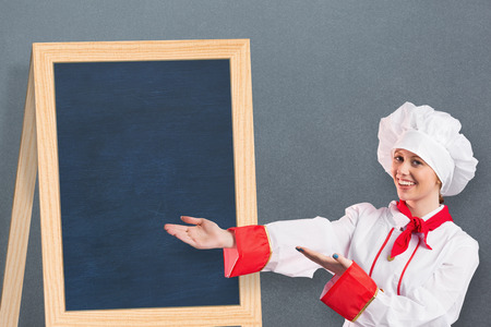 Pretty chef presenting with hands against greyの写真素材