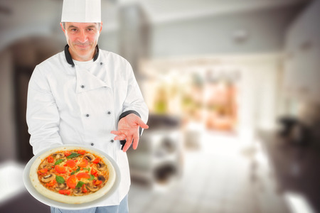 Chef displaying delicious pizza against kitchen in a stylish homeの写真素材