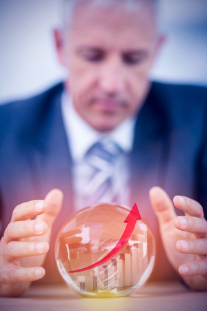 Red arrow and bar chart against businessman forecasting a crystal ballの写真素材