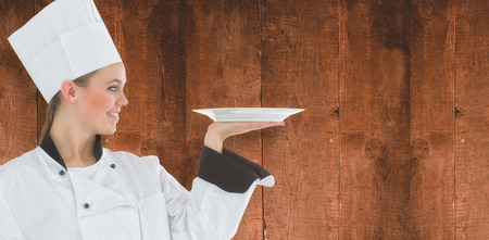 Composite image of woman chef holding a plate against a wooden backgroundの写真素材