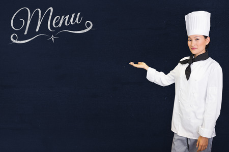 Confident female cook in the kitchen against navy blueの写真素材