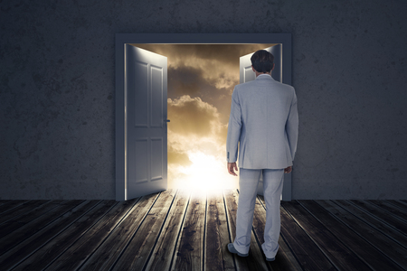 Rear view of businessman walking on white background against open big door on wallの写真素材