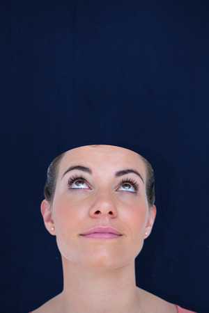 Close-up of beautiful woman looking up against navy blueの写真素材