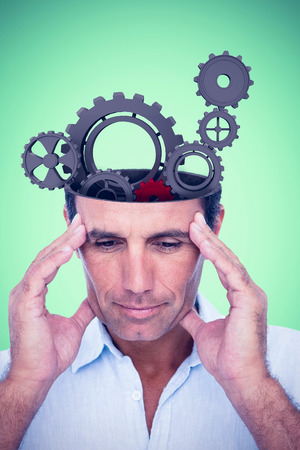 Handsome man thinking with hand on forehead against green backgroundの写真素材