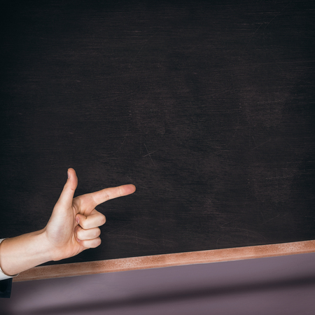 Hand pointing against black chalkboardの写真素材