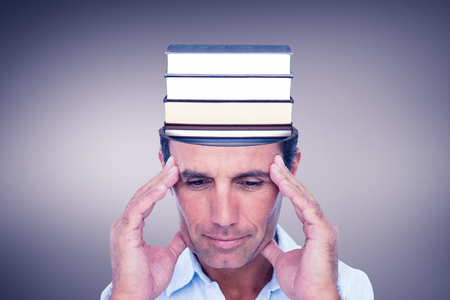 Handsome man thinking with hand on forehead against grey vignetteの写真素材