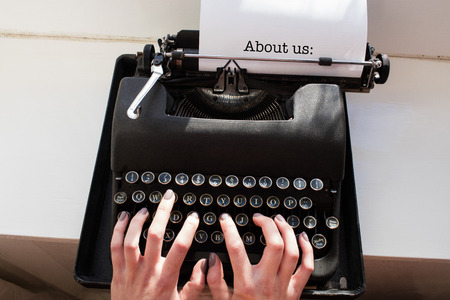 The word about us: against womans hand typing on typewriterの写真素材
