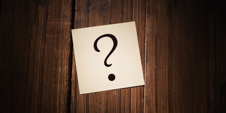 question mark against white paper fallen on wooden flooring