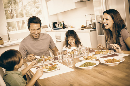 Family laughing around a good meal in kitchenの写真素材