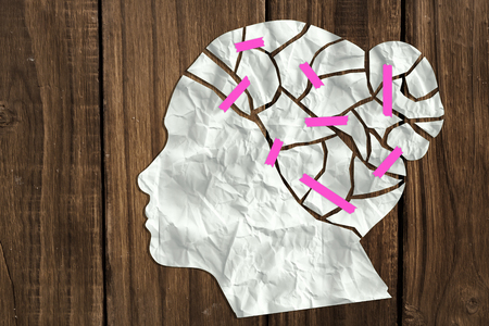 Composite image of sheet of paper in shape of head of woman against a wooden backgroundの写真素材