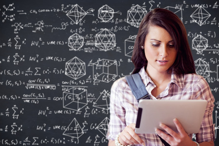 Maths against young focused student using a tablet computer