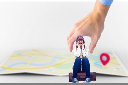 Smiling hipster woman sitting on suitcase  against mapの写真素材