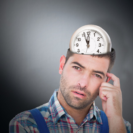 Portrait of confused manual worker scratching head against digitally generated grey vignette...