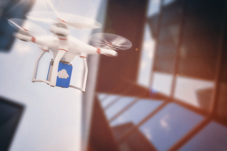 Digital image of a drone holding a cube against low angle view of skyscraper on a sunny dayの写真素材