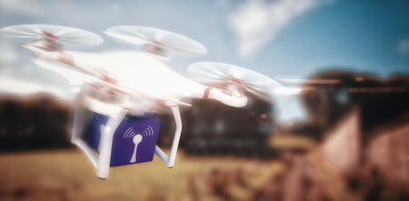 Digital image of a drone holding a cube against view of the countryside