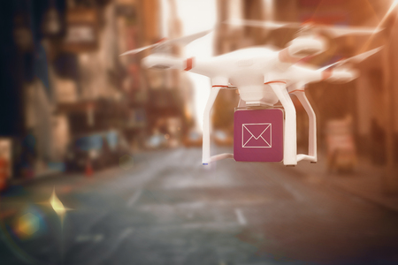 Digital image of a drone holding a cube against picture of a cityの写真素材