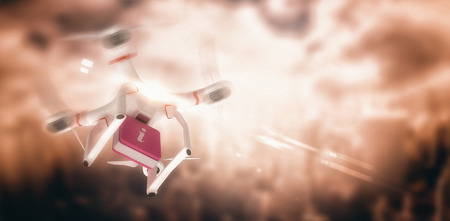 Digital image of a drone holding a cube against aerial view of a city on a cloudy dayの写真素材