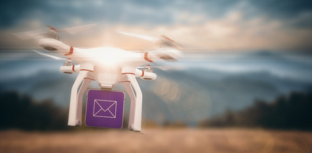 Digital image of a drone holding a cube against beautiful scene of trees and mountainの写真素材