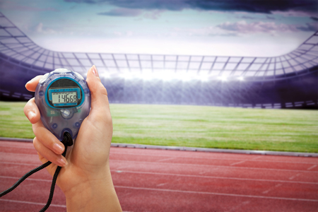 Close up of a hand holding a timer on a white background against race trackの写真素材