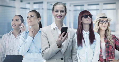 Laughing stylish businesswoman holding smartphone against modern room overlooking cityの写真素材