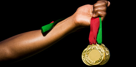 Hand holding three gold medals on white backgroundの写真素材