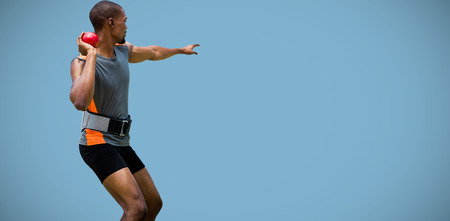 Rear view of sportsman practising shot put  against blue backgroundの写真素材