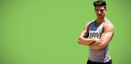 Portrait of handsome sportsman is posing with crossed arms  against green background