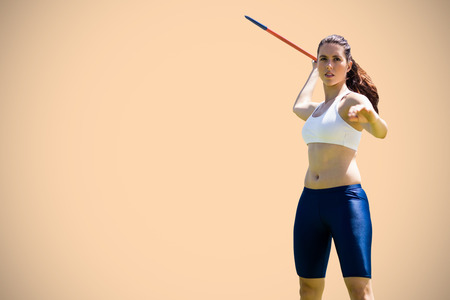 Woman throwing javeline against orange backgroundの写真素材