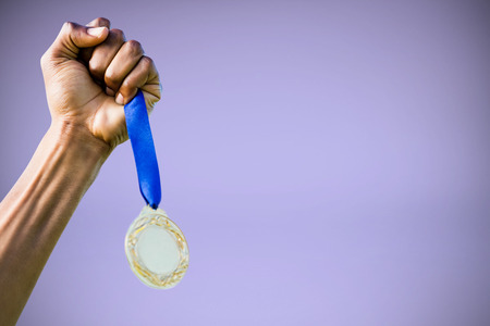Hand holding a silver medal on white background against purple backgroundの写真素材