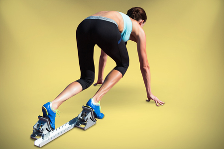 Athlete woman in the starting-block against yellow backgroundの写真素材