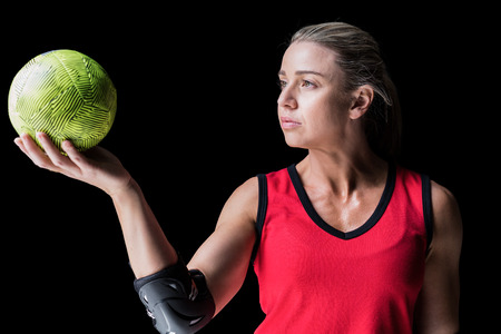 Female athlete with elbow pad holding handball on black backgroundの写真素材