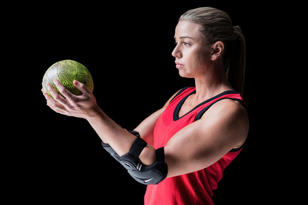 Female athlete with elbow pad holding handball on black backgroundの写真素材