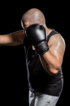 Side view of boxer hitting straight on black backgroundの写真素材
