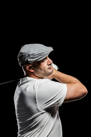 Portrait of golf player taking a shot on black backgroundの写真素材