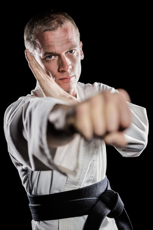 Portrait of fighter performing karate stance on black backgroundの写真素材