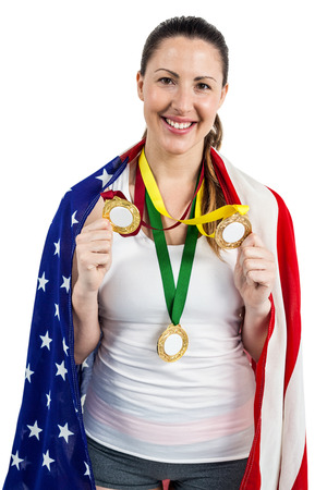 Athlete with gold medals around his neck posing with american flag after victory on white backgroundの写真素材