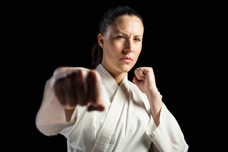 Female fighter performing karate stance on black backgroundの写真素材