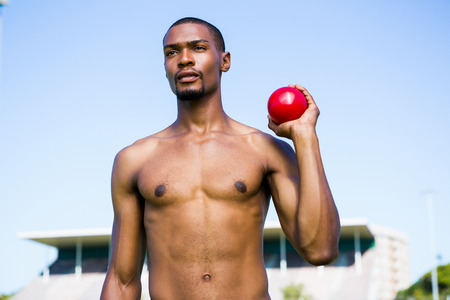 Determined male athlete holding short put ball in a stadiumの写真素材