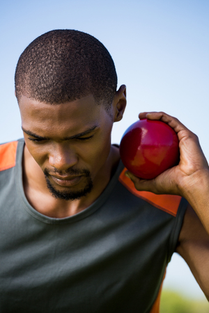 Close-up of male athlete holding shot put ball in stadiumの写真素材