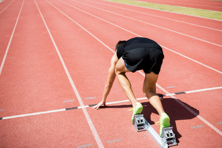 Rear view of an athlete ready to run on running trackの写真素材