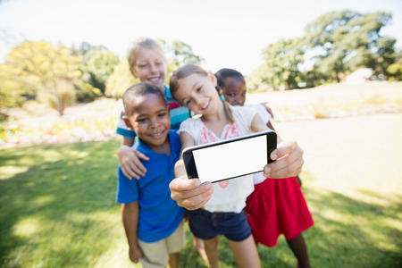Kids are taking a selfie during a sunny day at parkの写真素材