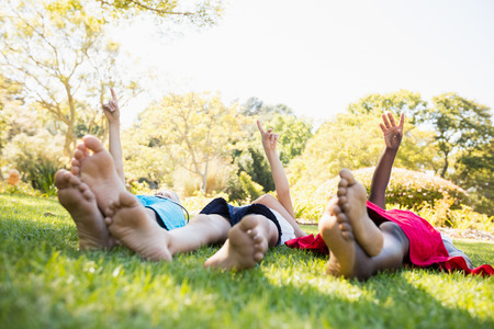 Kids are lying on the grass during a sunny day at parkの写真素材