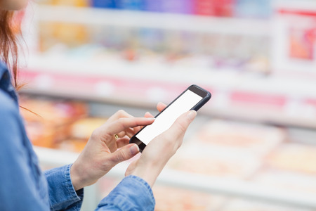 Hands using a smartphone in a supermarketの写真素材