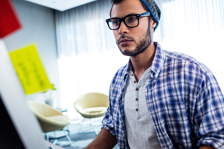 Focus on hipster man working at computer desk in studio