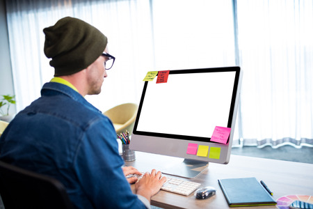 Side view of casual man working at computer desk in modern office