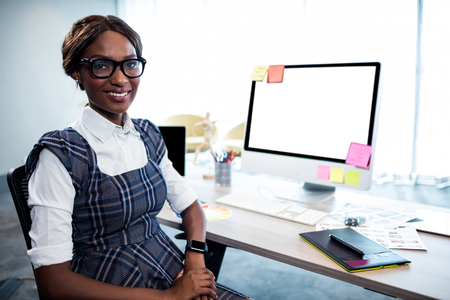 Smiling businesswoman posing with computer in the officeの写真素材